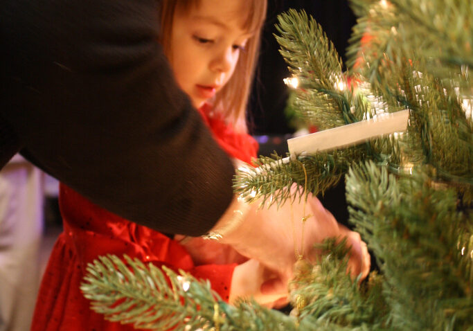 A young guest hangs a memorial ornament during the annual Remembrance Tree Ceremony. 